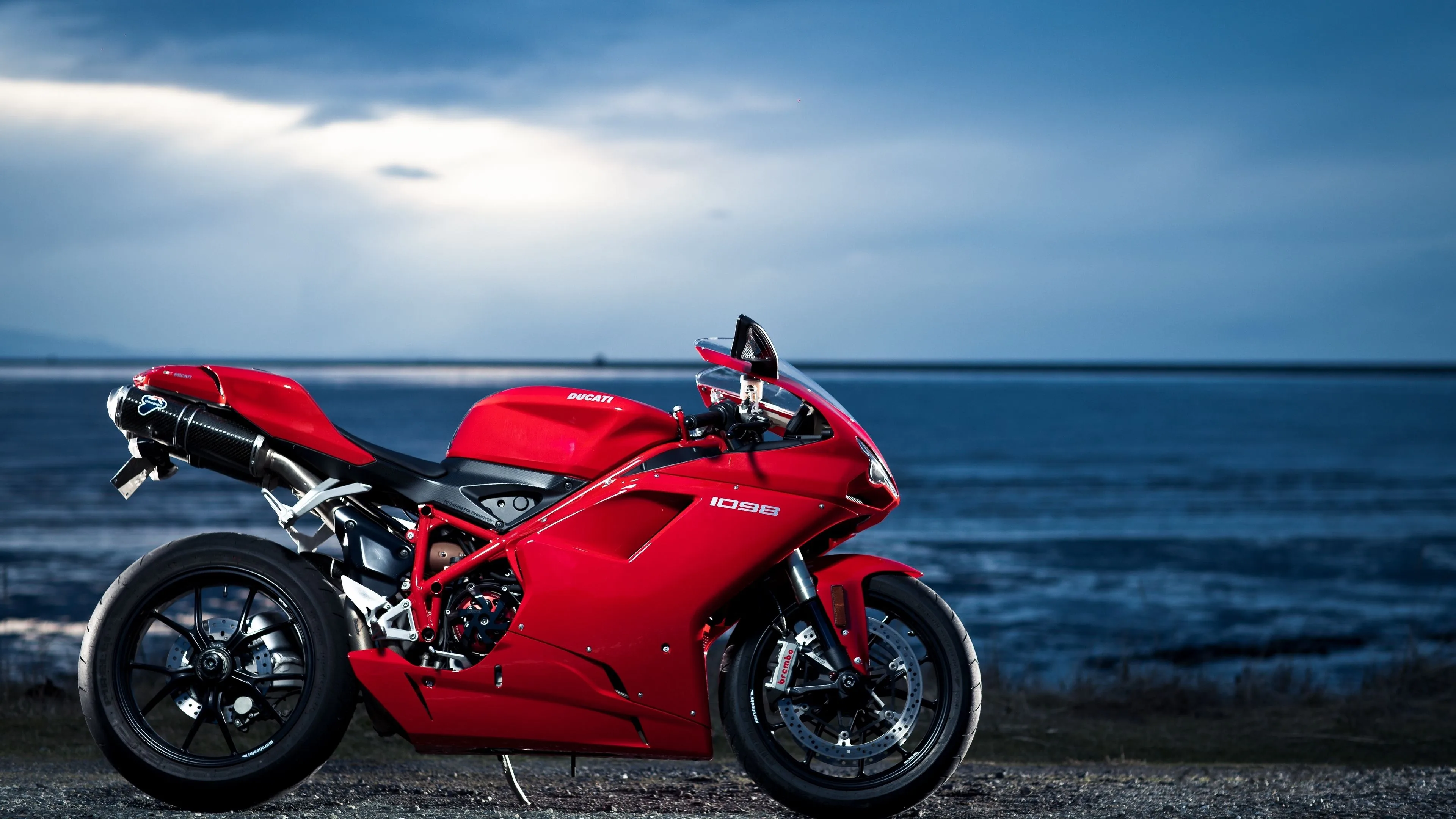 A Red Motorcycle Parked Next To The Ocean