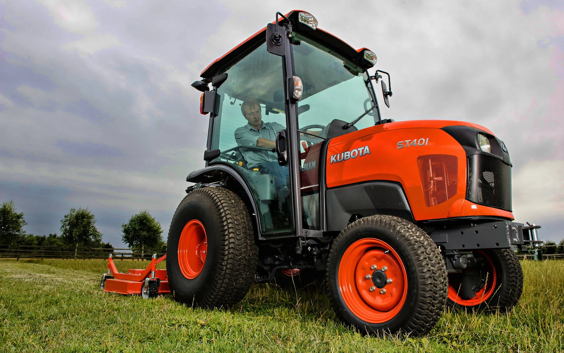 Download Man Driving Orange Kubota Tractor Wallpaper